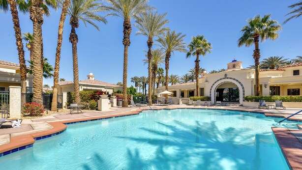 A swimming pool surrounded by palm trees and a building with a tiled roof. - Pool & Hot Tub Access: La Quinta Vacation Home (La Quinta)