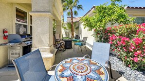 An outdoor patio with a mosaic table, chairs, a grill, and a small garden with pink flowers. - Pool & Hot Tub Access: La Quinta Vacation Home (La Quinta)