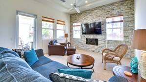 A spacious living room with a stone wall, a flat-screen TV, a fireplace, and comfortable seating. - Pool & Hot Tub Access: La Quinta Vacation Home (La Quinta)