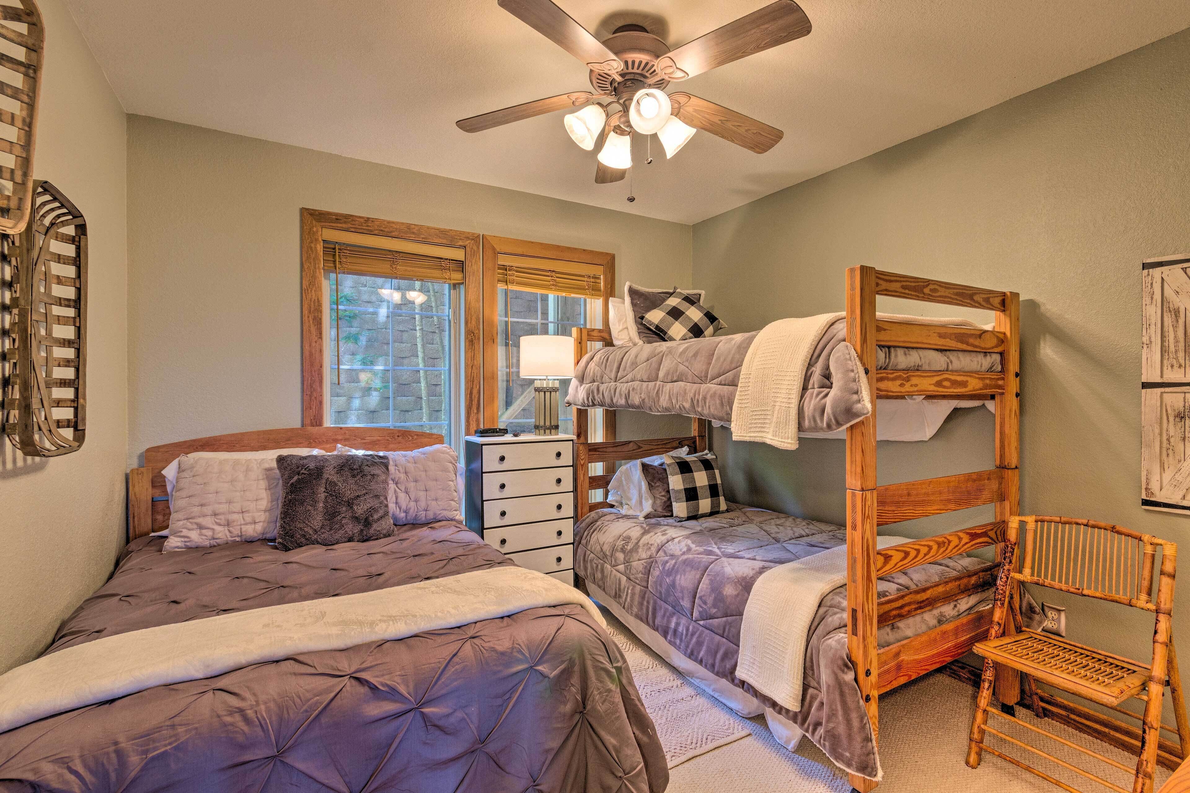 A bedroom with two beds, a ceiling fan, a window, and a wooden chair.