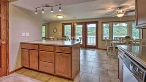 A kitchen with wooden cabinets, a large island, and a dining area with a view of the outdoors. - Private Dock! Waterfront Group Haven in Camdenton (Camdenton)