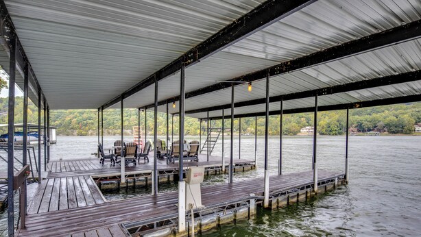 A covered dock with wooden planks, metal railings, and a water pump. - Private Dock! Waterfront Group Haven in Camdenton (Camdenton)