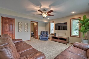 A living room with a ceiling fan, a large window, a television, and a potted plant.