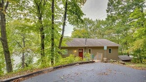 A cabin with a front porch, a small deck, and a view of a lake surrounded by trees. - Private Dock! Waterfront Group Haven in Camdenton (Camdenton)
