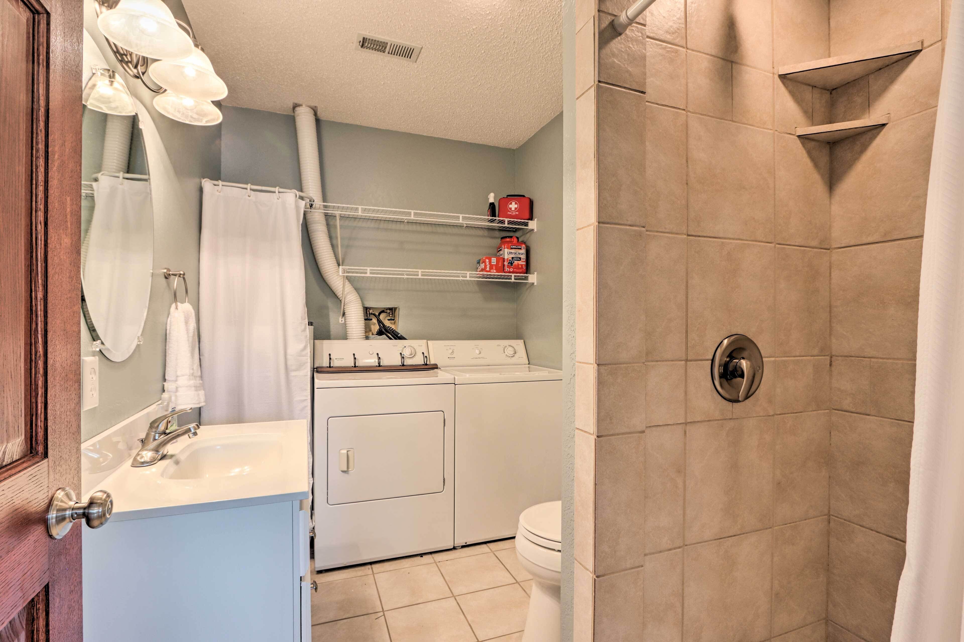 A compact bathroom with a washing machine, a toilet, and a shower area.