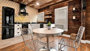 A kitchen with a round dining table, wire mesh chairs, and wooden flooring. - The Duet 1 BR- Just Steps from Baylor University and Minutes from The Silos (Waco)