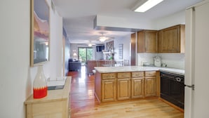 A kitchen with wooden cabinets, a marble countertop, and a built-in dishwasher. - Cozy Lake Ozark Condo Rental w/ Grill, Pool Access (Lake Ozark)