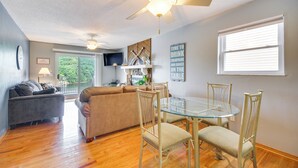 A living room with a glass dining table, beige sofa, and a ceiling fan. - Cozy Lake Ozark Condo Rental w/ Grill, Pool Access (Lake Ozark)