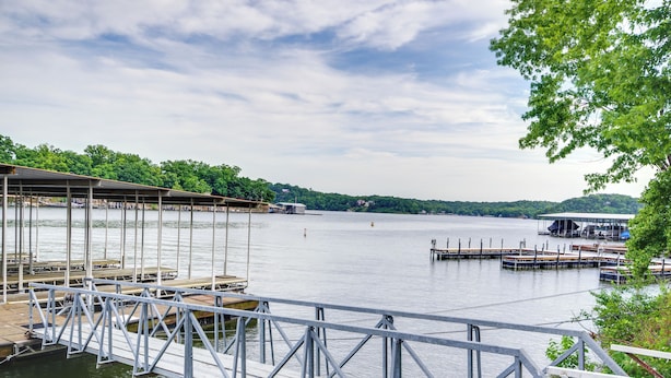 A lakeside dock with a covered seating area and a boat dock. - Cozy Lake Ozark Condo Rental w/ Grill, Pool Access (Lake Ozark)