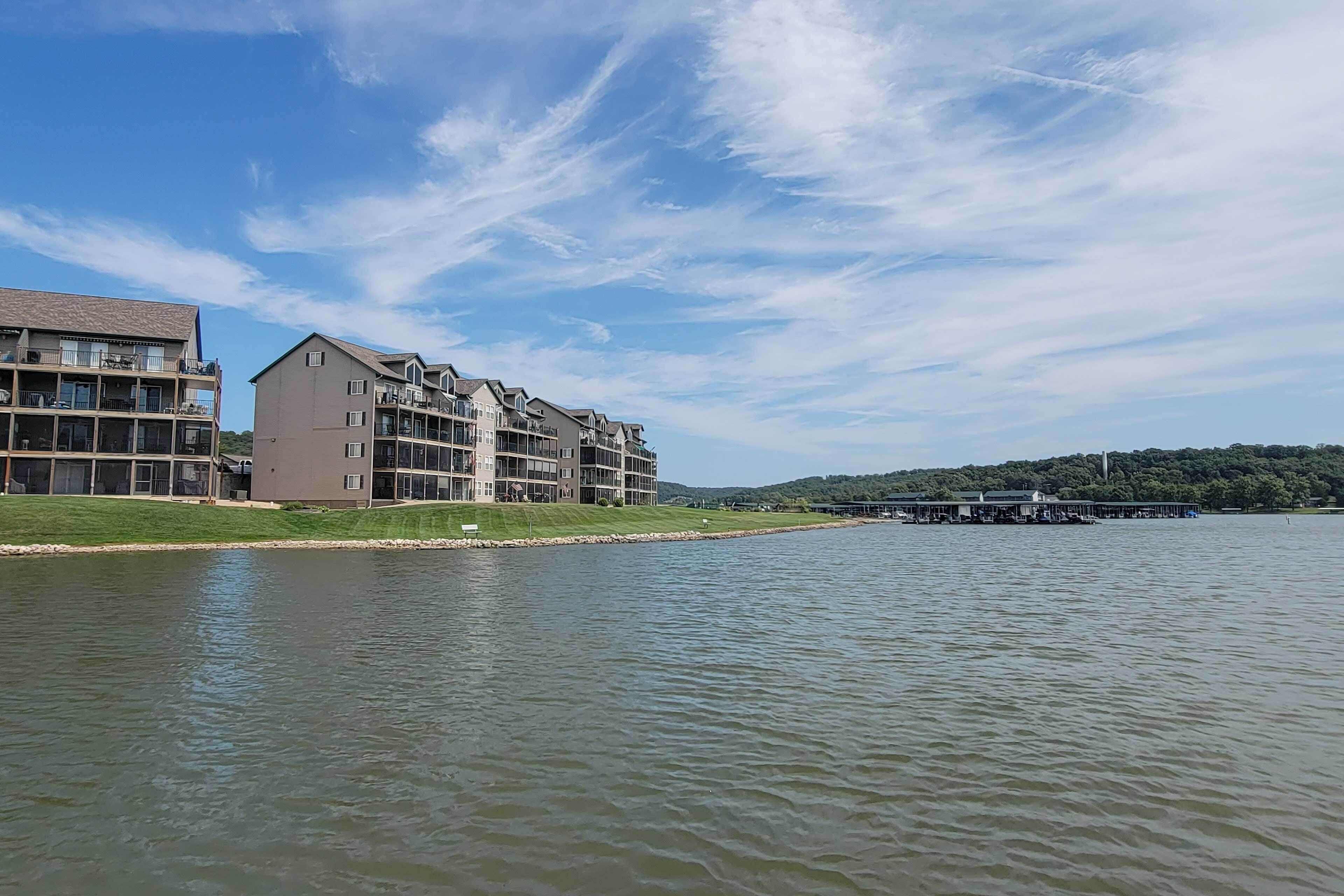 A waterfront hotel with multiple floors, balconies, and a dock extending into the water.