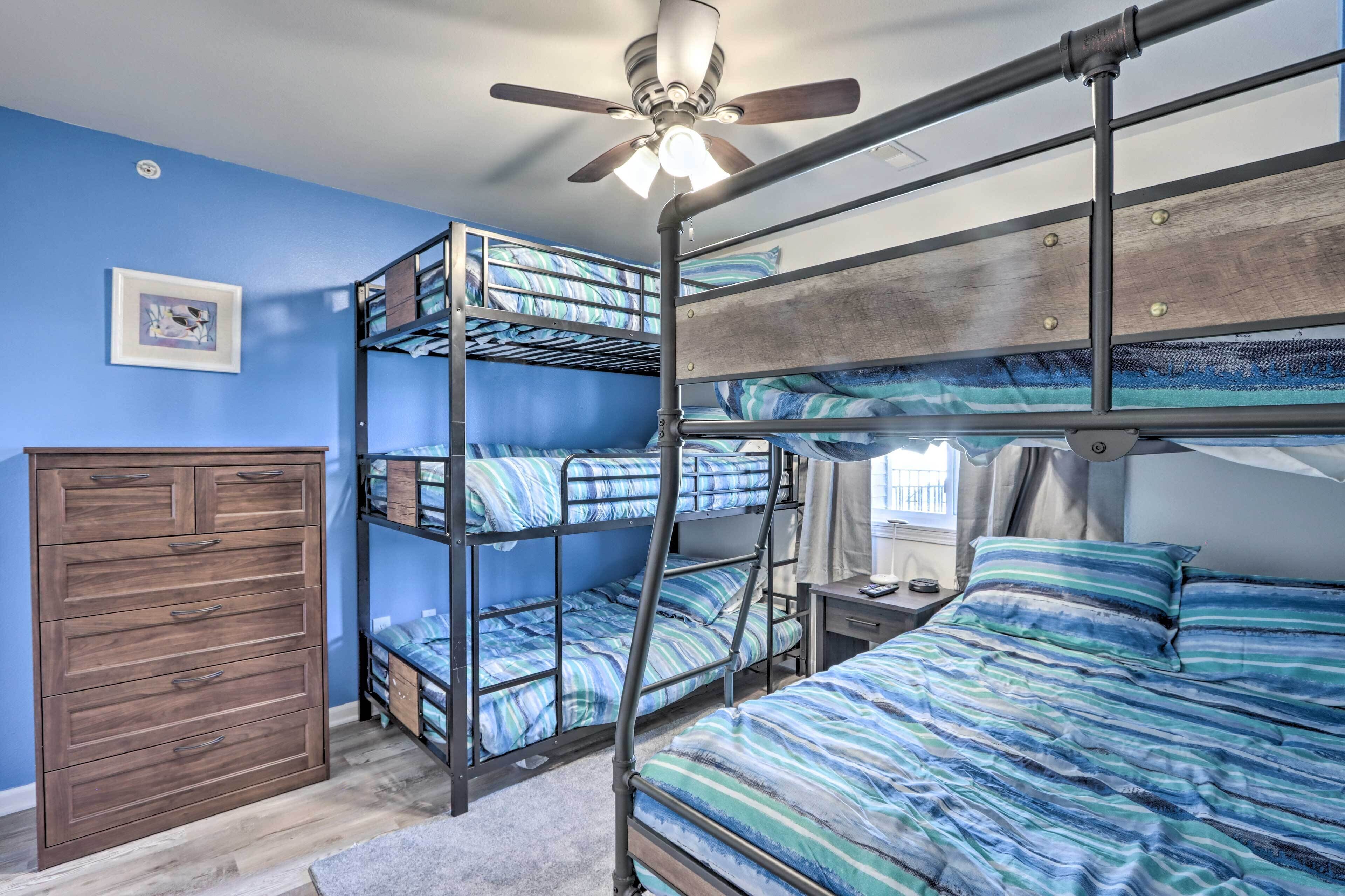 Habitación con literas, ventilador de techo, cómoda y un cuadro en la pared.