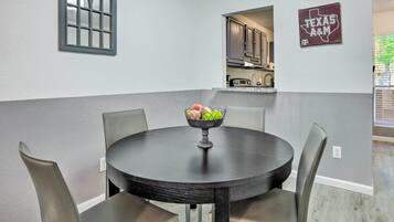 A dining area with a round table, four chairs, and a bowl of fruit.