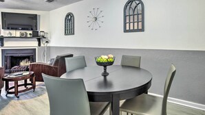 A dining area with a round table, four chairs, a bowl of fruit, a fireplace, and two arched windows. - Pet-friendly Bryan Escape ~ 2 Mi to Texas A & M (Bryan)