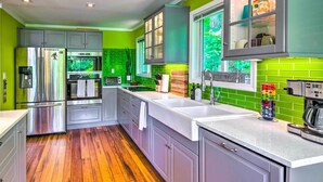 A modern kitchen with stainless steel appliances, green backsplash, and wooden flooring. - Mtn-view Gem in Lake Lure w/ Game Room & Fire Pit (Lake Lure)