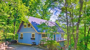 A blue house with a sloped roof, surrounded by trees and a gravel driveway. - Mtn-view Gem in Lake Lure w/ Game Room & Fire Pit (Lake Lure)