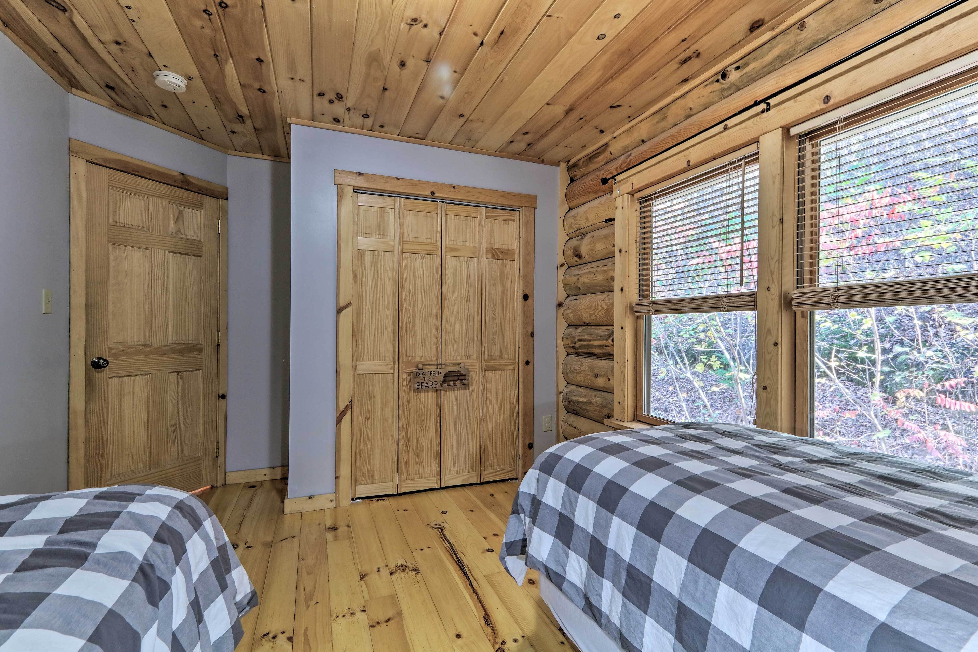 Ein Schlafzimmer mit zwei Betten, Holzboden und einem großen Fenster mit Jalousien.