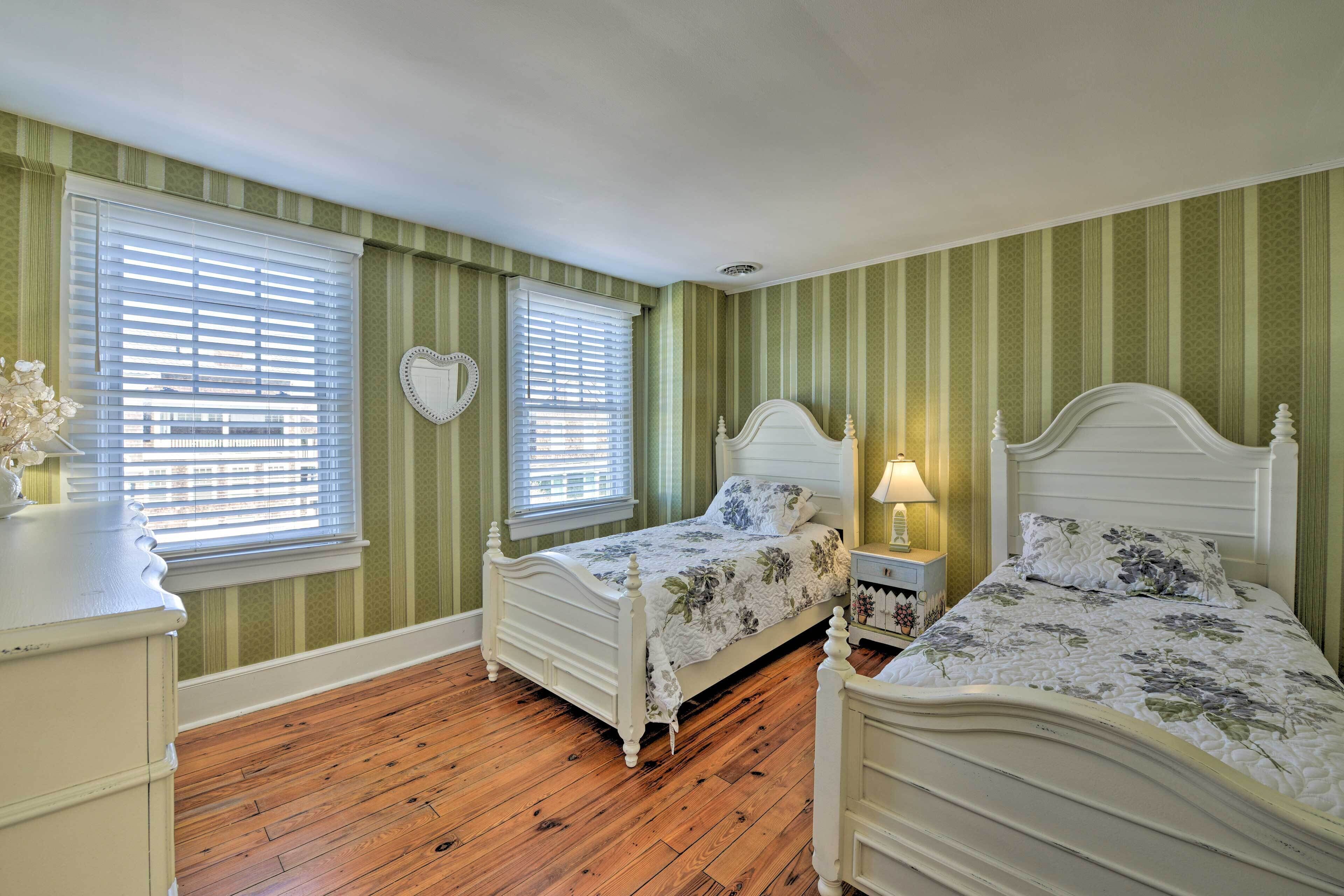 A bedroom with two beds, a dresser, and a nightstand.