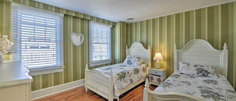A bedroom with two beds, a dresser, and a nightstand.