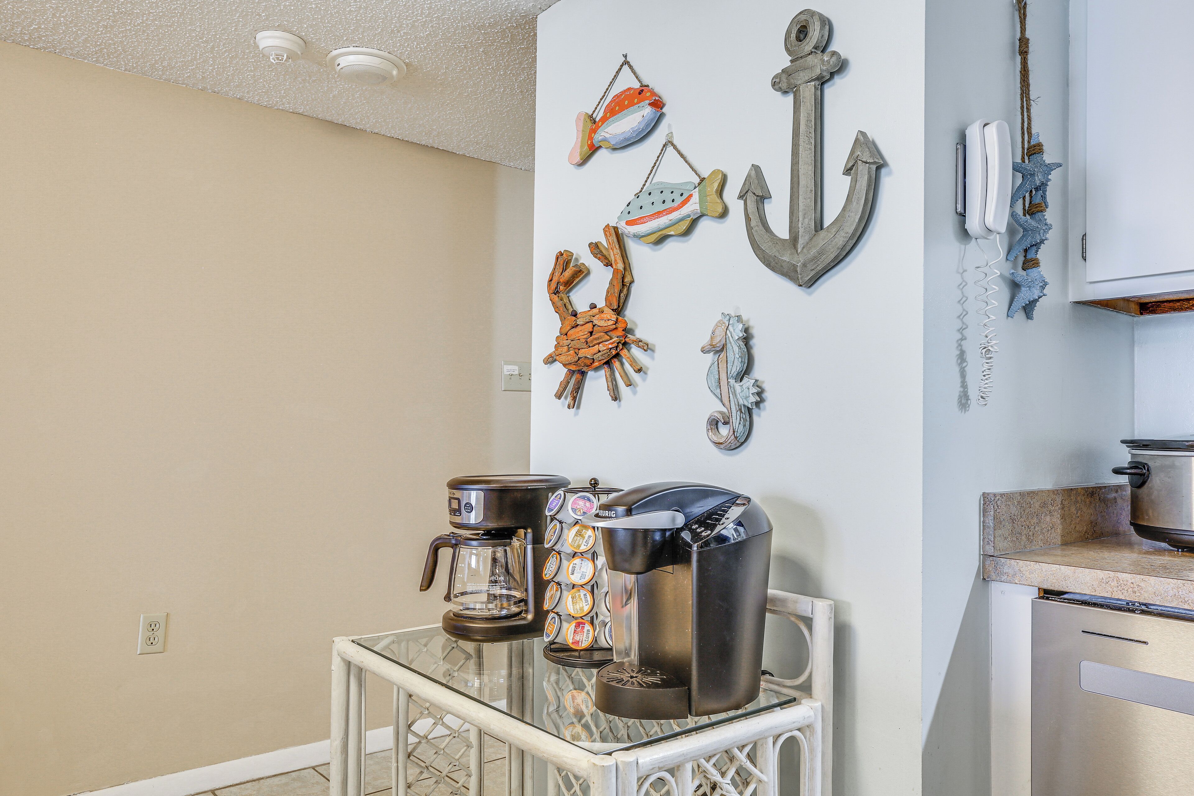 A kitchen with a coffee maker, a kettle, and a toaster on a glass table.