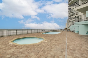 A rooftop pool area with two pools, a metal railing, and a staircase leading to an upper level. - Oceanfront Garden City Beach Condo For Families! (Murrells Inlet)