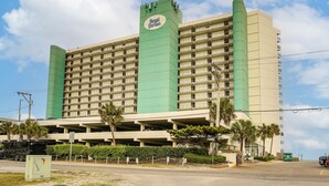A multi-story hotel with a prominent green and beige color scheme, a sign reading 'Royal Garden,' and a parking garage beneath. - Oceanfront Garden City Beach Condo For Families! (Murrells Inlet)