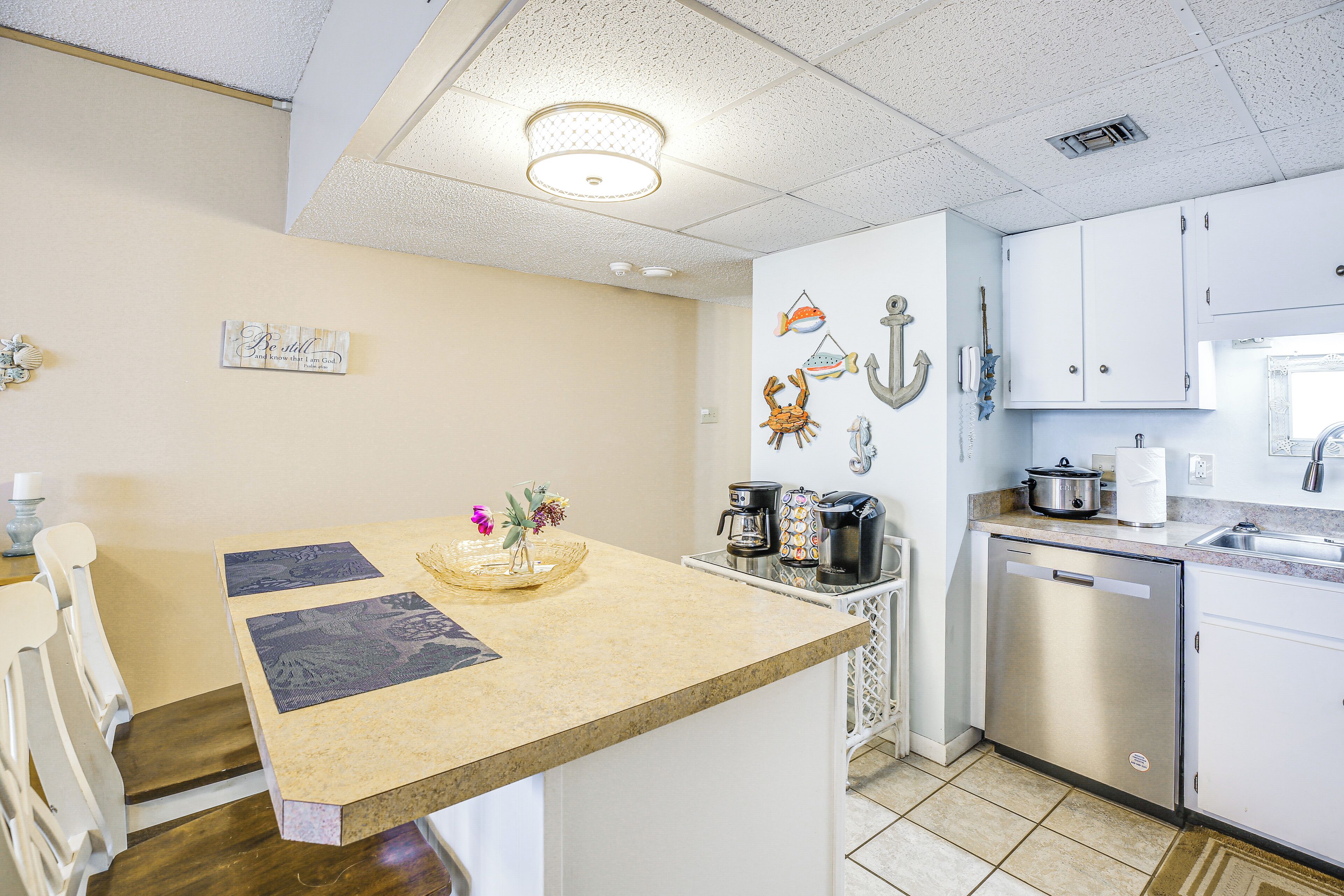 A kitchen with a countertop, a coffee maker, a dishwasher, and a wall-mounted oven.