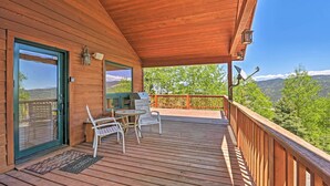A wooden deck with a covered area, outdoor seating, and a scenic mountain view. - Angel Fire Mountain-view Retreat w/ Private Deck! (Angel Fire)