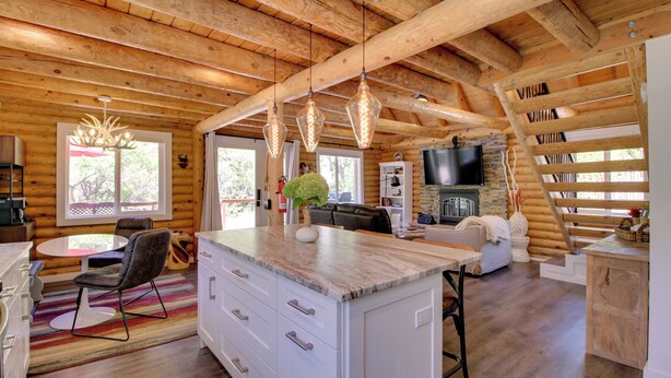 A log cabin interior with a kitchen, dining area, and living room.