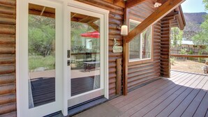 A log cabin with a wooden deck, large glass doors, and a sign reading "Casa del Rio."