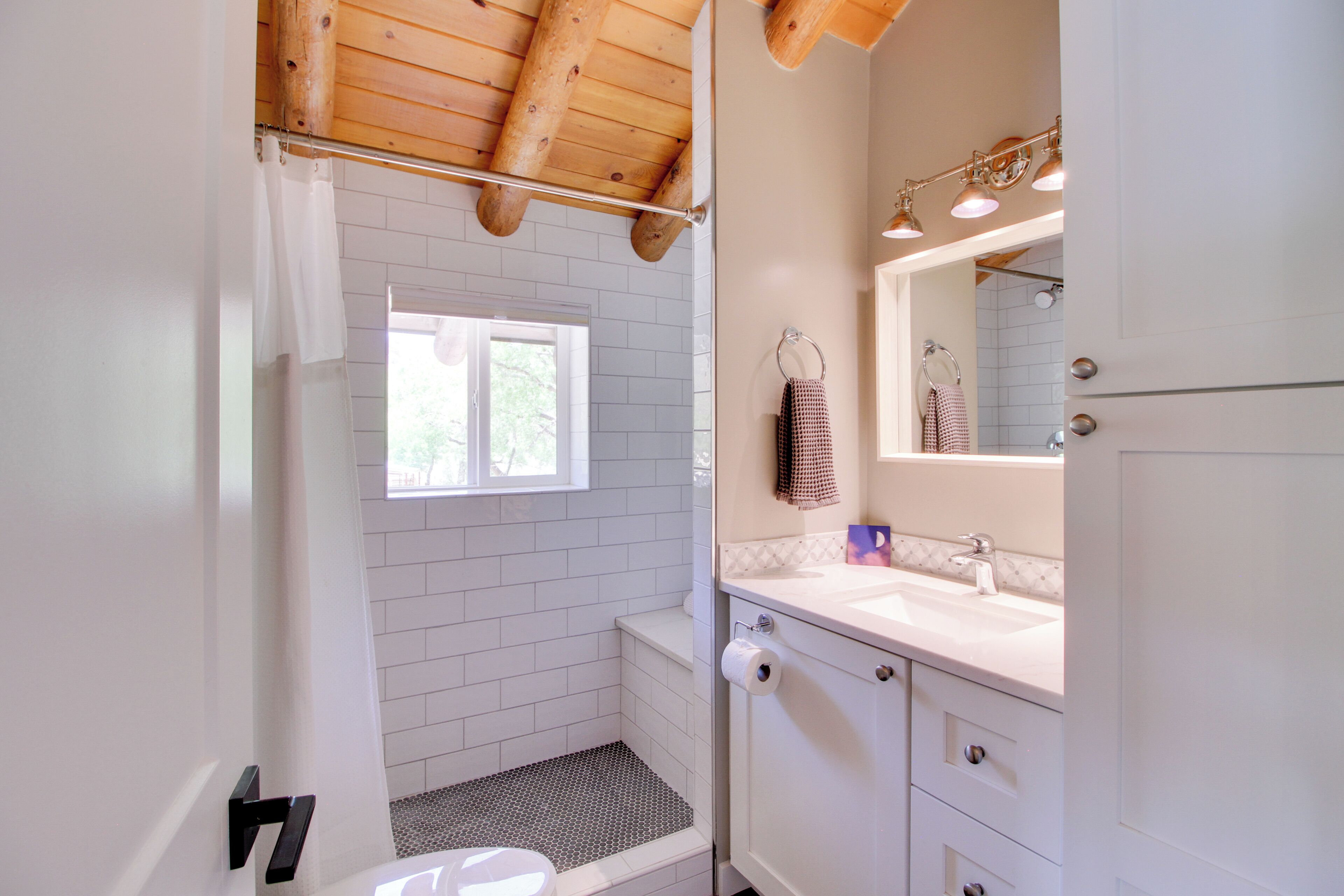 A bathroom with a shower, a toilet, a sink, and a mirror.