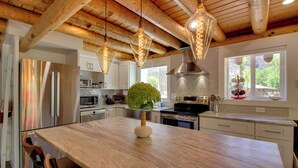 A modern kitchen with wooden beams, stainless steel appliances, and pendant lighting.