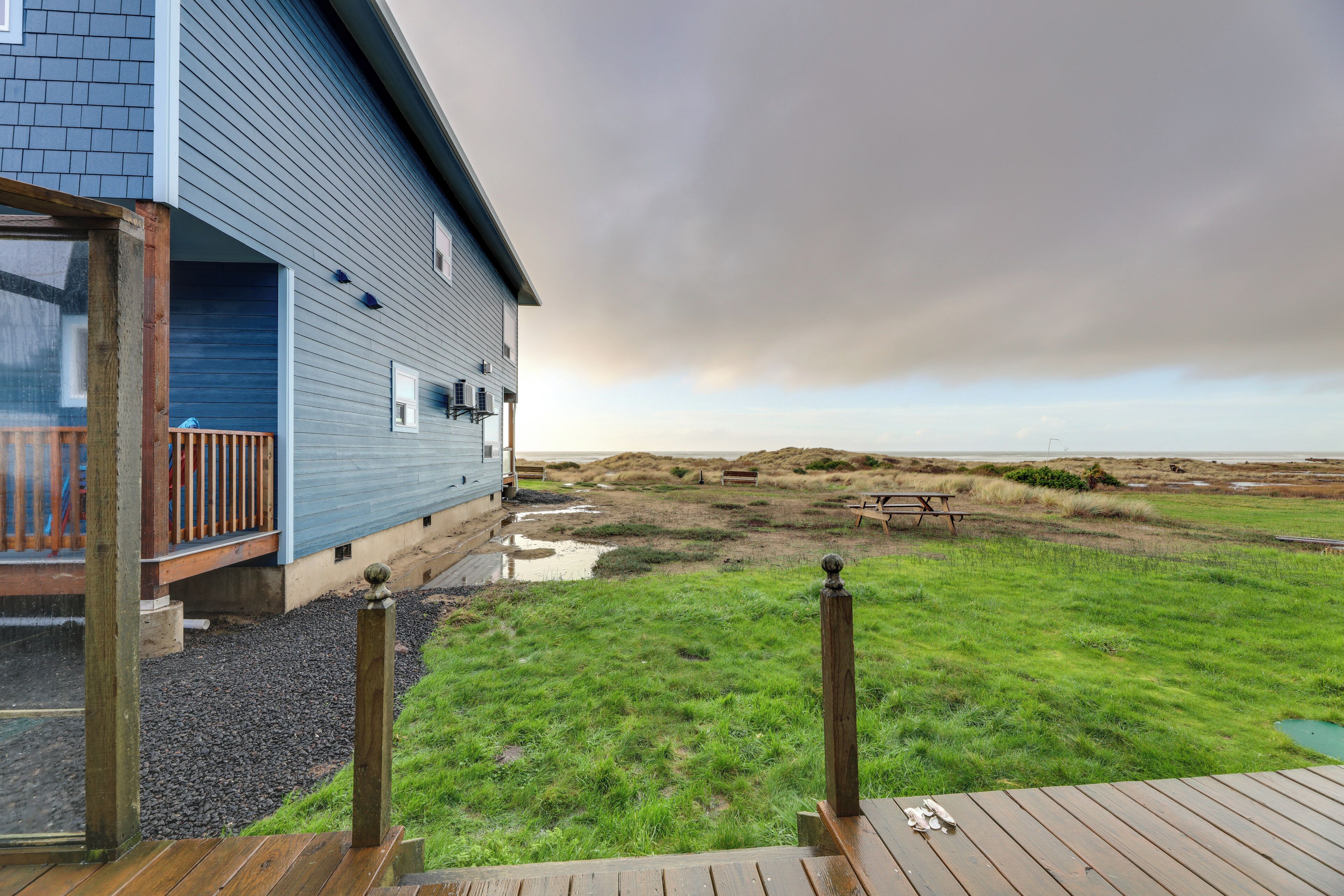 Una casa con terraza, jardín césped y vista a la playa.