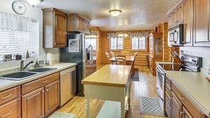 A kitchen with wooden cabinets, a central island, stainless steel appliances, and pendant lighting.