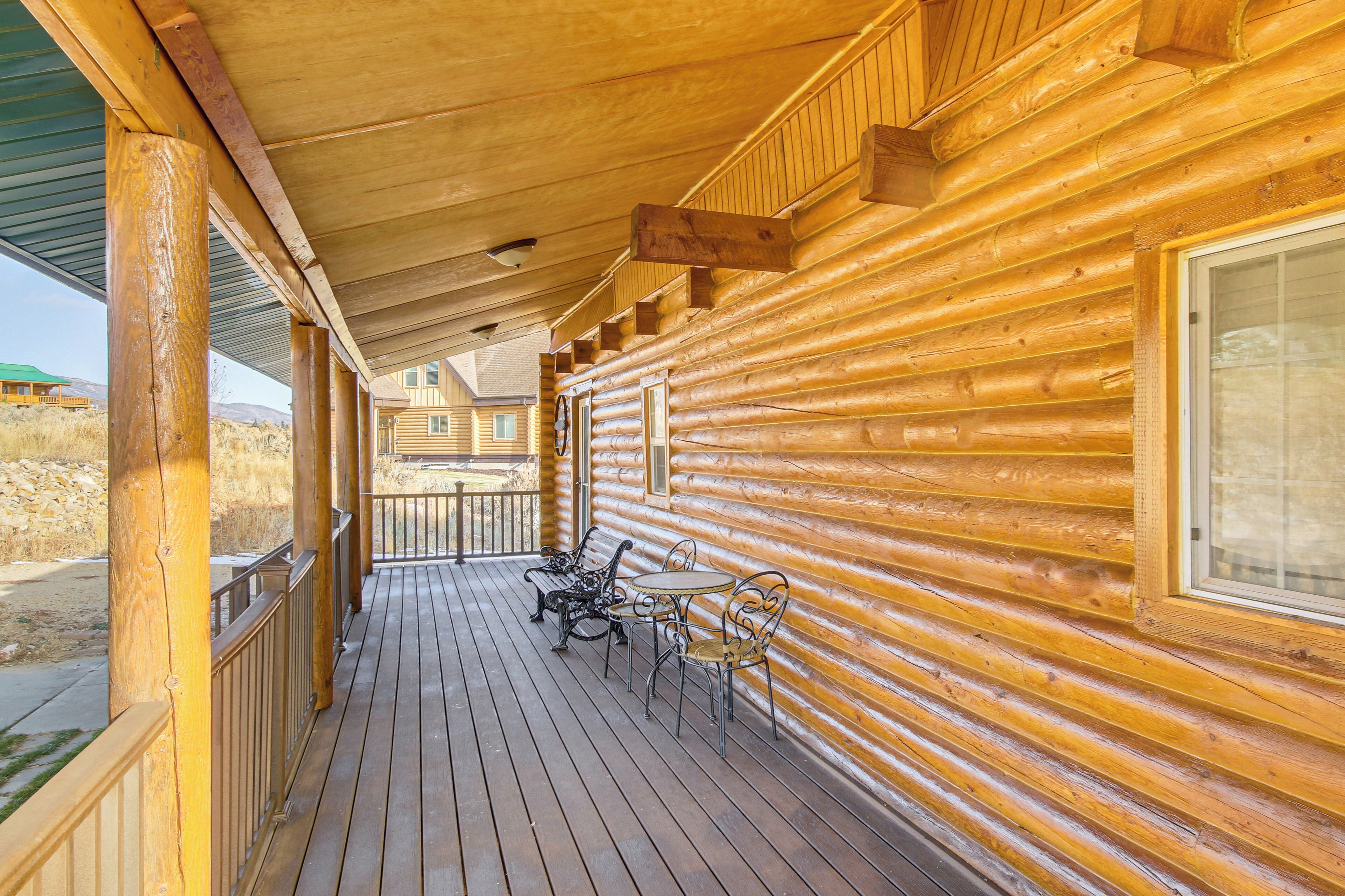 Eine Holzhütte mit überdachter Veranda, Sitzgelegenheiten im Freien und Blick auf die umliegende Landschaft.