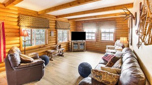 A log cabin interior with a leather sofa, a television, and wooden walls.