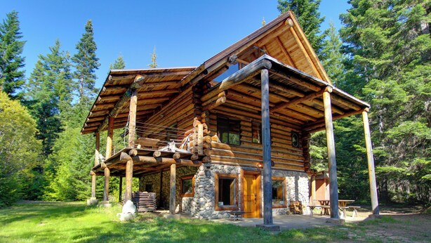 A log cabin with a stone foundation, wooden beams, and a covered porch. - Cozy Easton Cabin w/ Wenatchee Nat'l Forest Views! (Easton)
