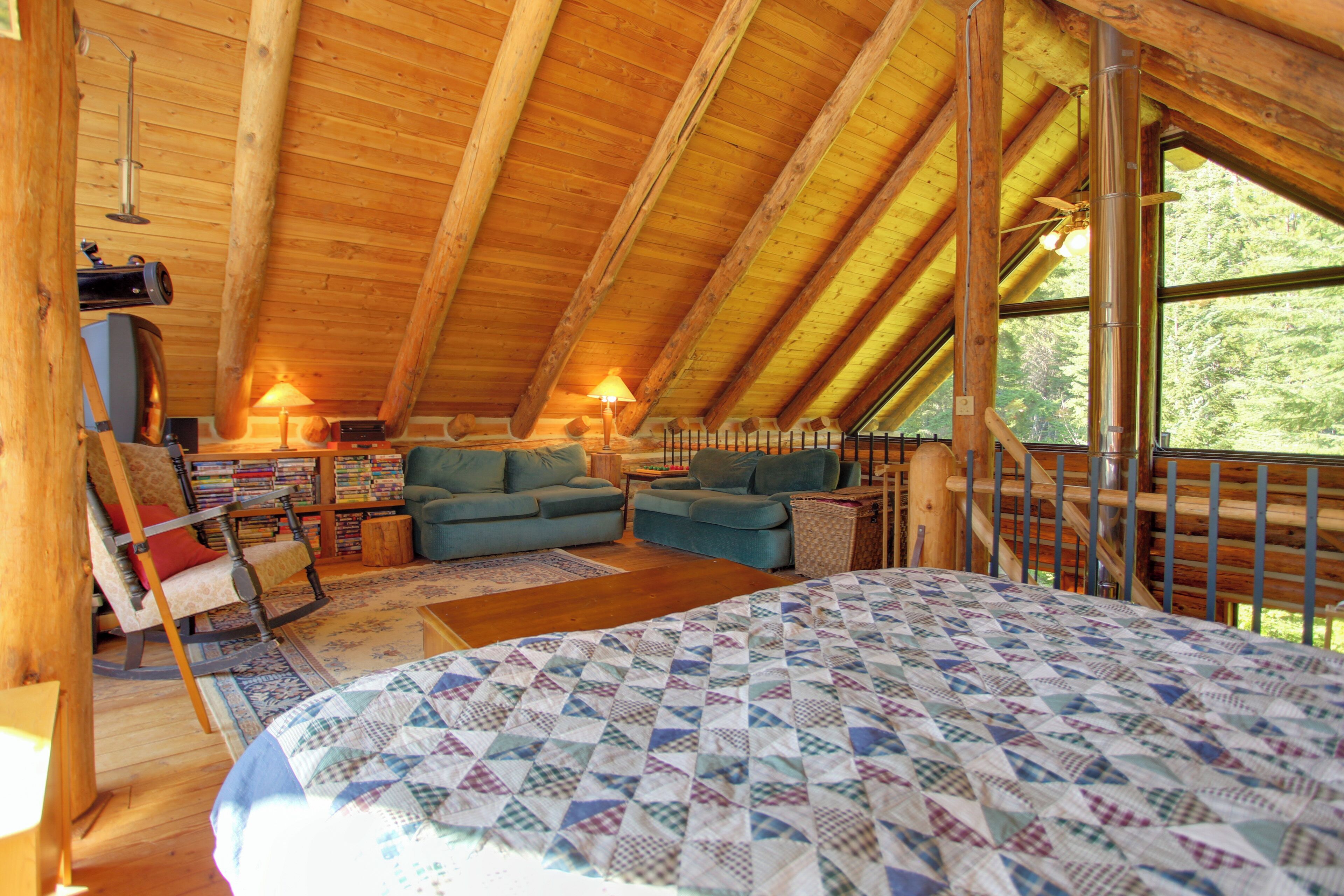 Un dormitorio acogedor en el ático con una cama grande, dos sofás, un sillón mecedora y una chimenea.