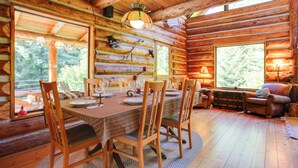 A log cabin interior with a dining table set for four, surrounded by wooden chairs. - Cozy Easton Cabin w/ Wenatchee Nat'l Forest Views! (Easton)