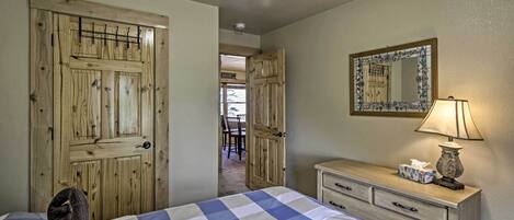 A bedroom with a bed, a dresser, a lamp, a mirror, and a door.