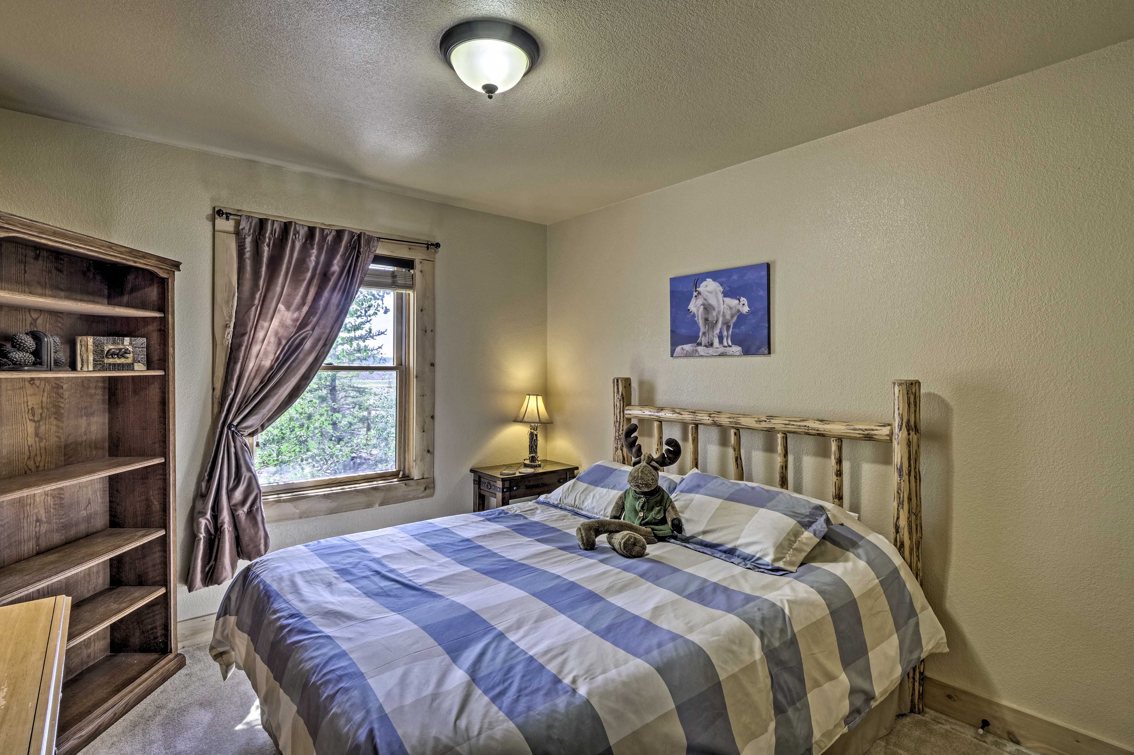 Une chambre à coucher avec un lit, une tête de lit en bois, une table de chevet avec une lampe, une fenêtre avec des rideaux et un tableau accroché au mur.
