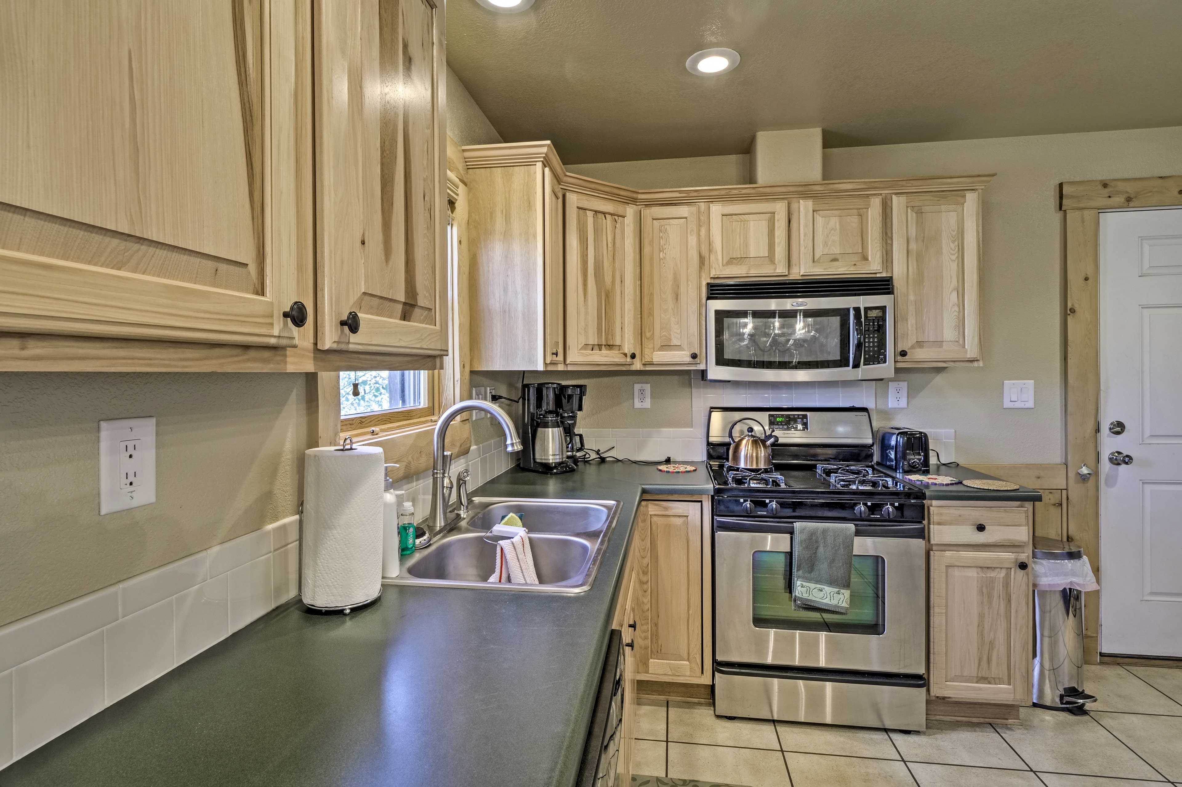 A kitchen with wooden cabinets, a stainless steel stove, a microwave, and a sink.