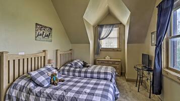 A bedroom with two beds, a desk, a TV, and a window with curtains.