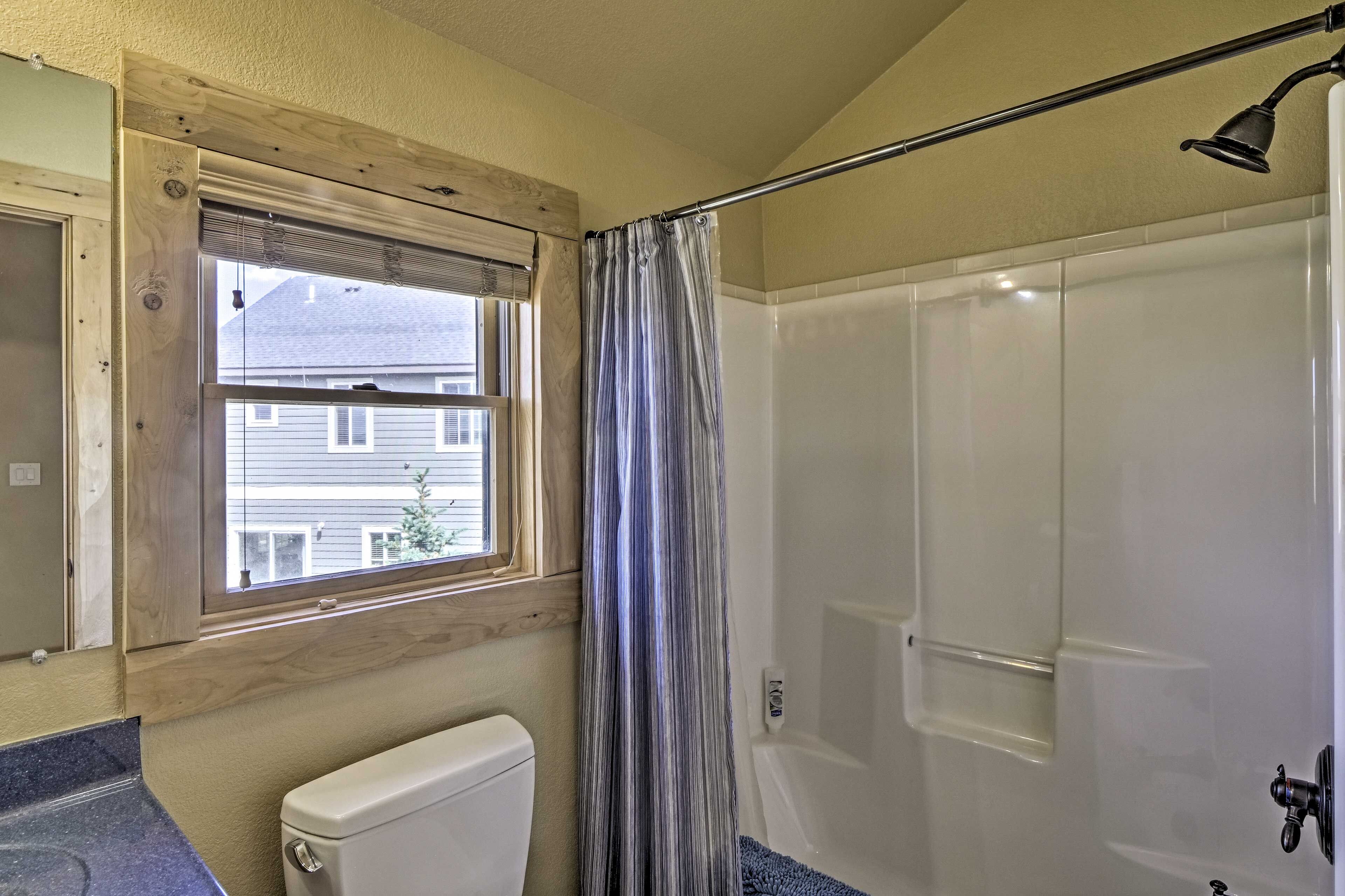 Un baño con inodoro, ducha, ventana y cortina.
