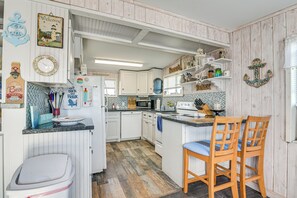A compact kitchen with white cabinetry, a microwave, a sink, and a wooden island with chairs. - 1 Mi to Surfside Beach: Bbq-ready Home in Freeport (Freeport)