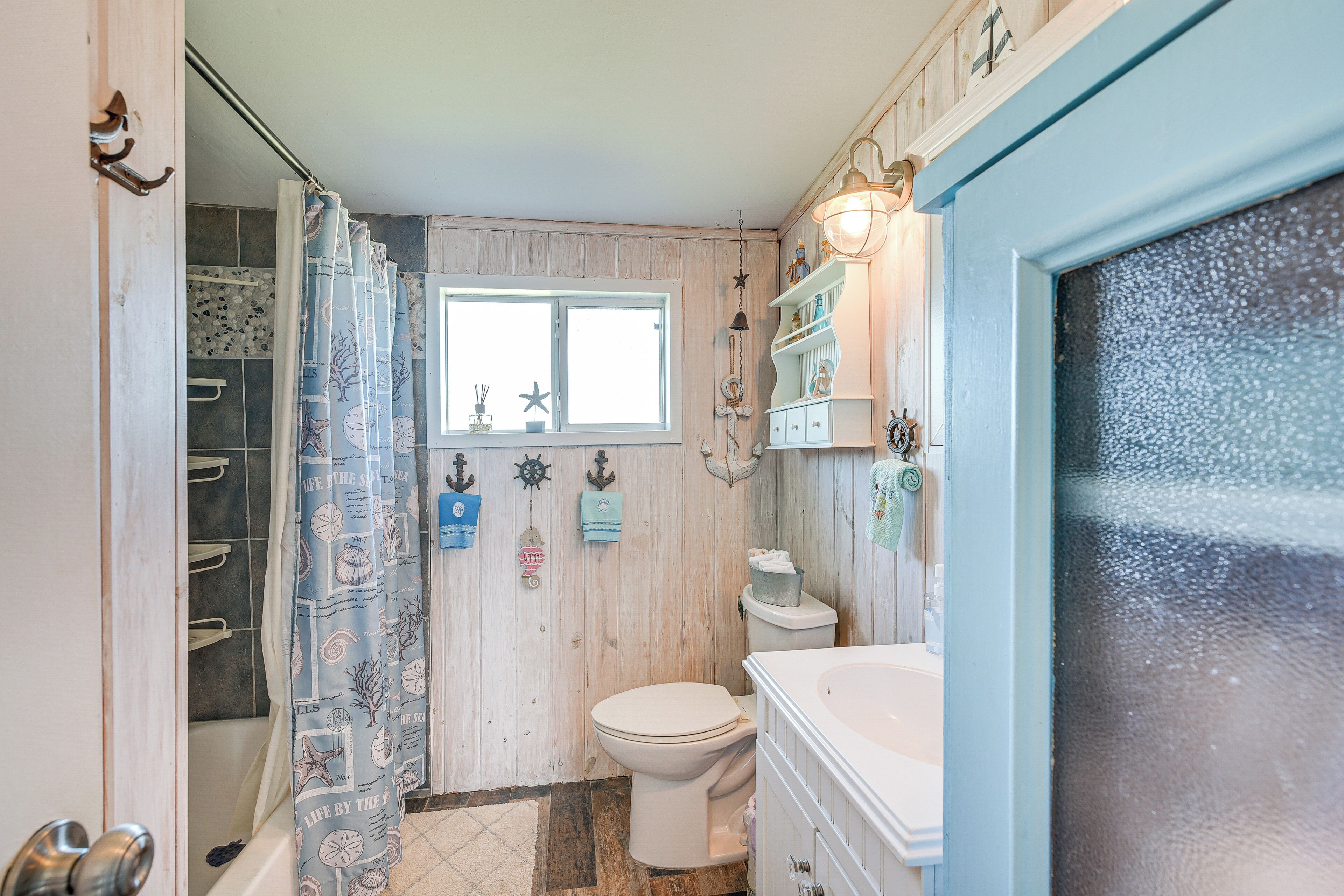 A bathroom with a shower curtain, toilet, and vanity.
