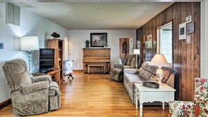 Ein Wohnzimmer mit Holzboden, einer Couch, einem Liegestuhl, einem Fernseher und einem Kamin.