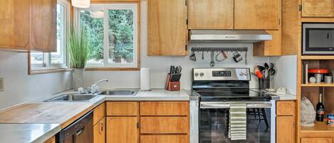 A kitchen with wooden cabinets, a stainless steel sink, a stove, and a microwave.