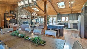 A spacious living area with a wooden dining table, comfortable seating, a stone accent wall, and a kitchen with modern appliances.