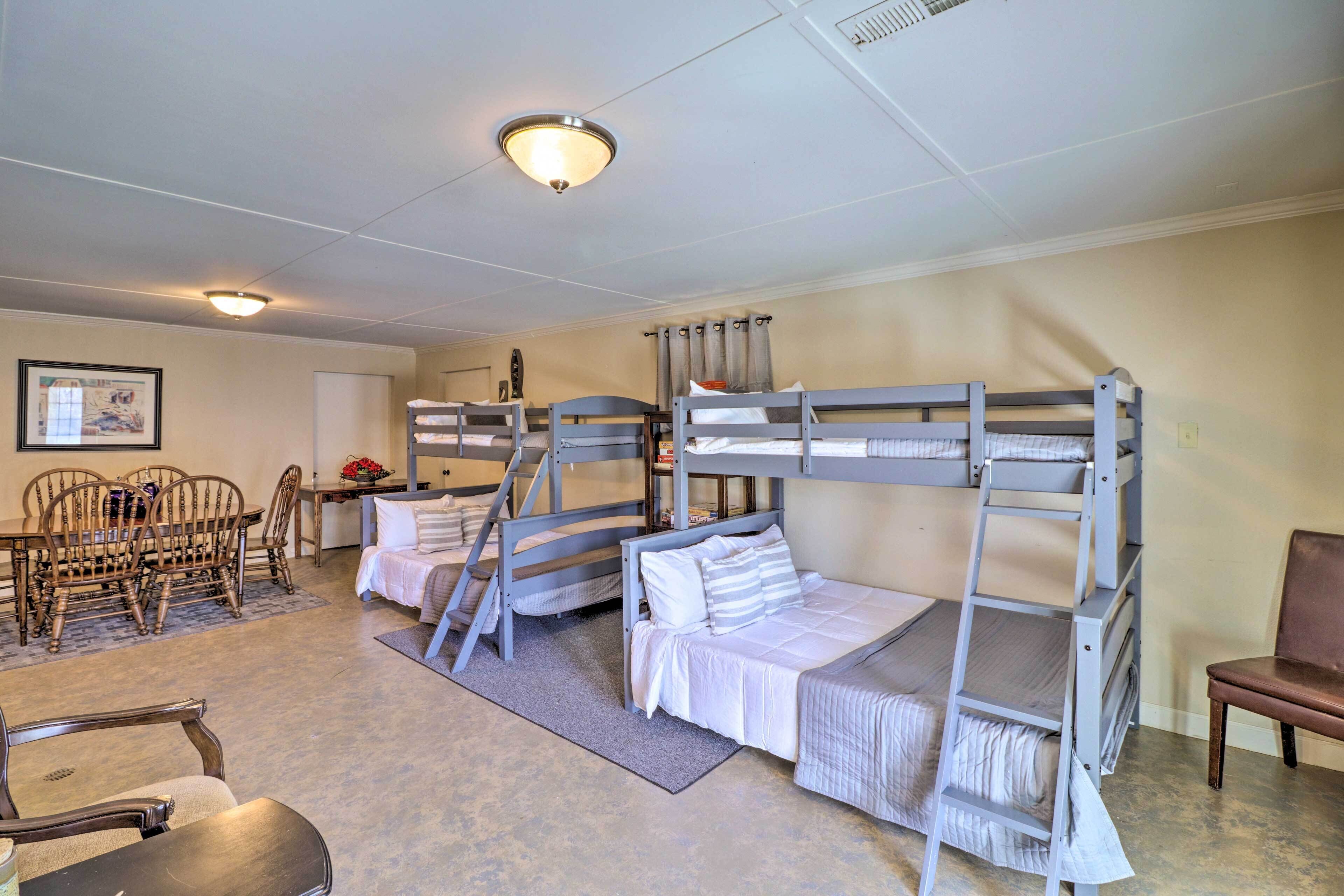 A room with bunk beds, a dining table with chairs, and a small table with a vase.