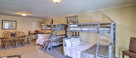 A room with bunk beds, a dining table with chairs, and a small table with a vase.